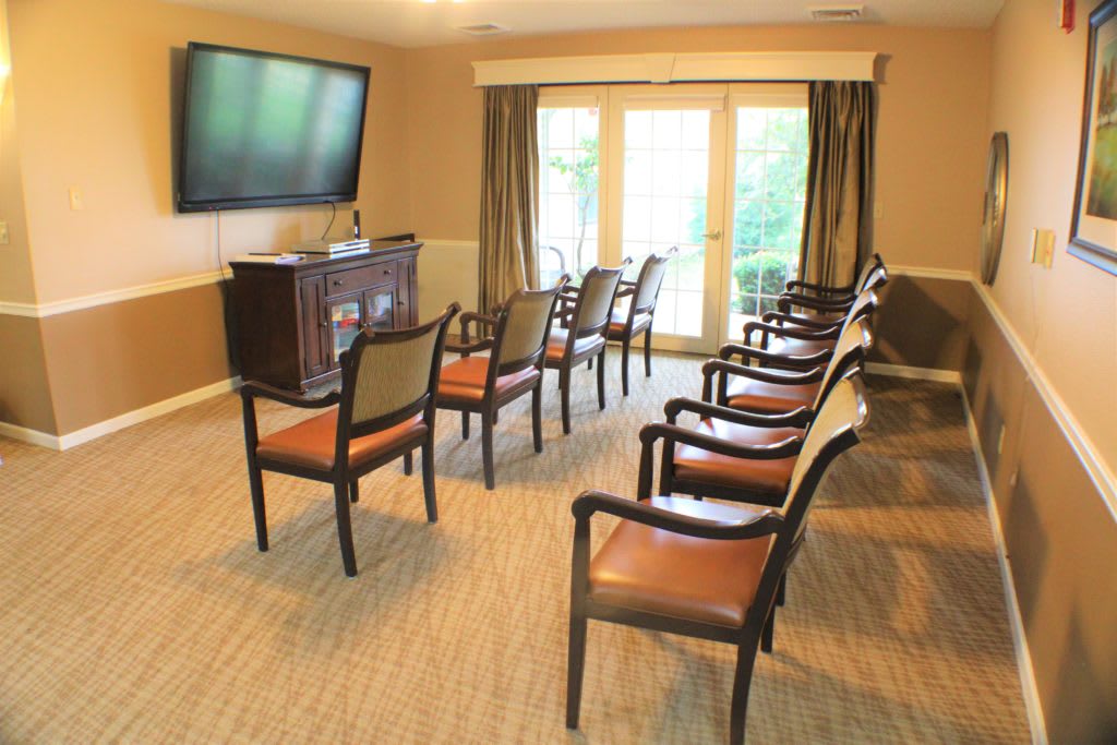 A small conference room setup with chairs facing a television and large windows.