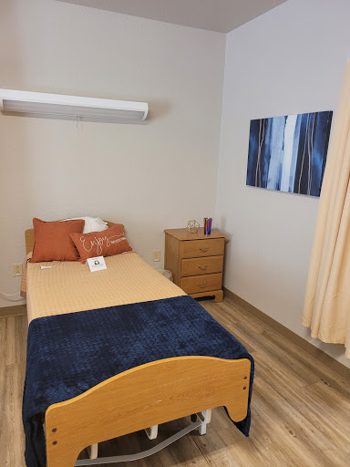 A cozy and minimalist bedroom setup featuring a single bed, wooden nightstand, and decorative elements.