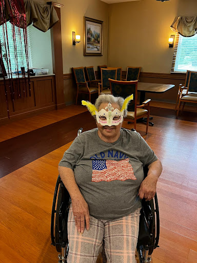 A joyful individual wearing a colorful mask and an American flag-themed shirt, seated in a wheelchair.