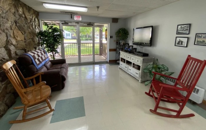 A cozy living room with a sofa, rocking chair, and television.