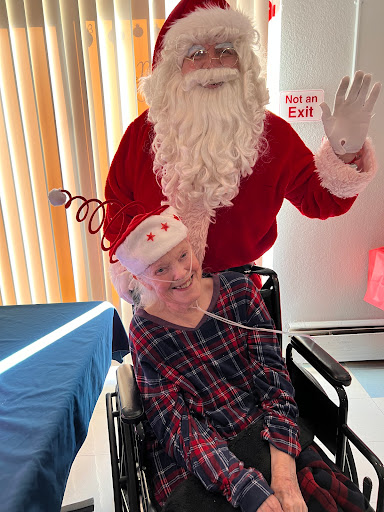 A joyful holiday moment featuring Santa Claus alongside a cheerful individual in a wheelchair.