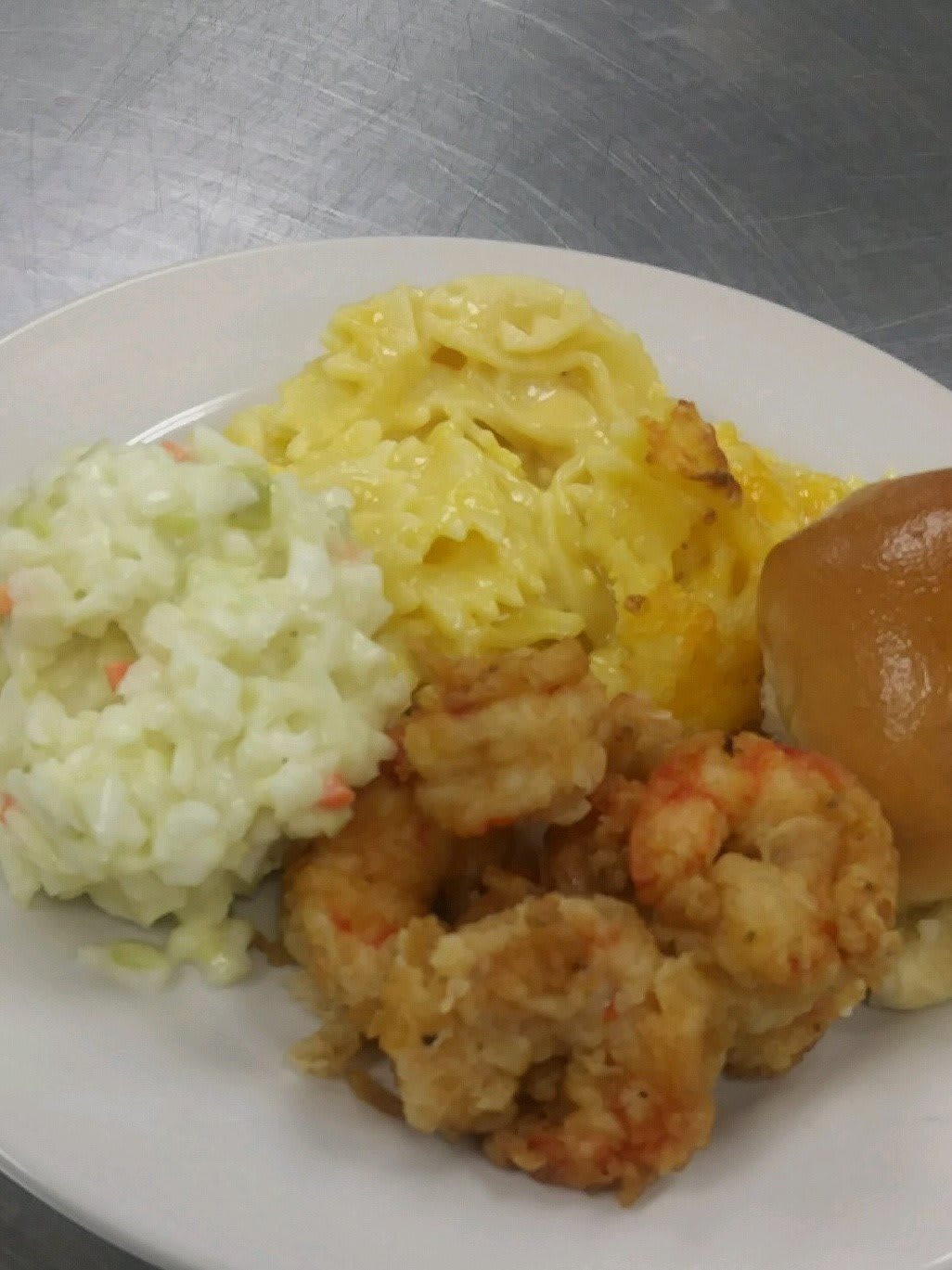 A plate of fried shrimp served with coleslaw, mac and cheese, and a bread roll.