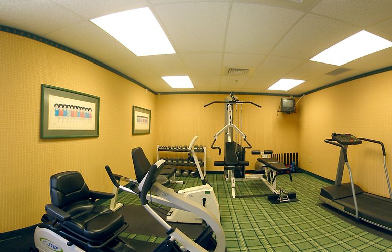 A compact gym room equipped with various exercise machines and weights.