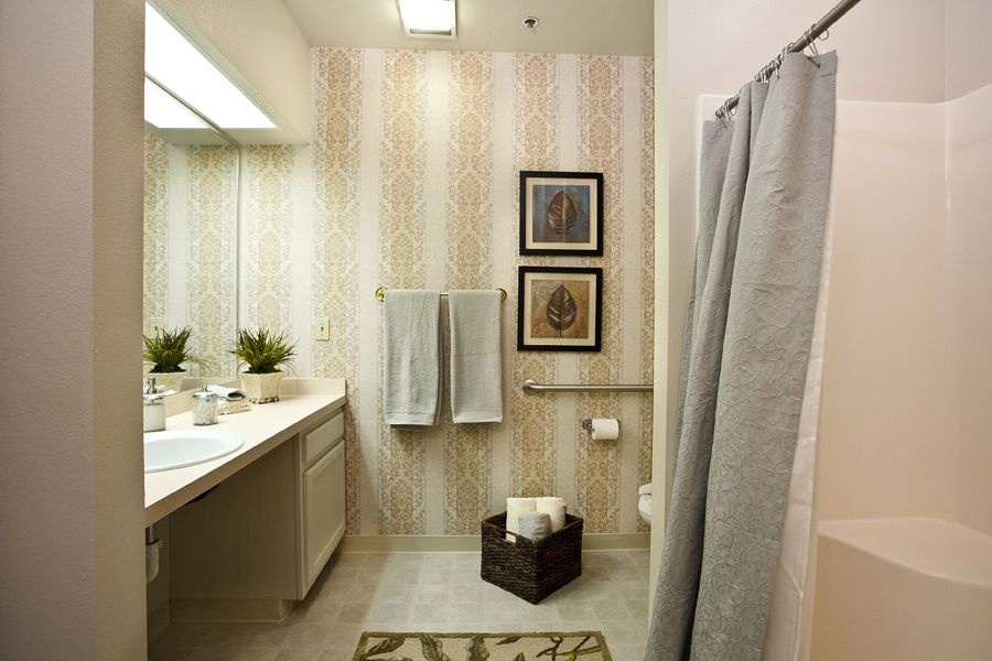 A well-decorated bathroom interior with towels, wall art, and plants.