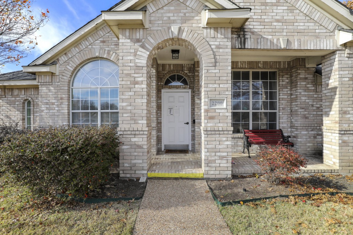 Front entrance of a brick house with an archway and large windows.