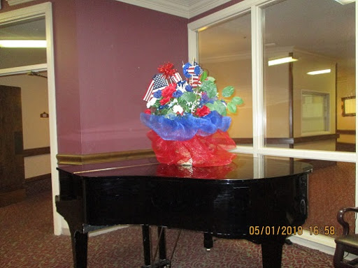 A beautifully arranged flower bouquet sits atop a black piano in an indoor setting.