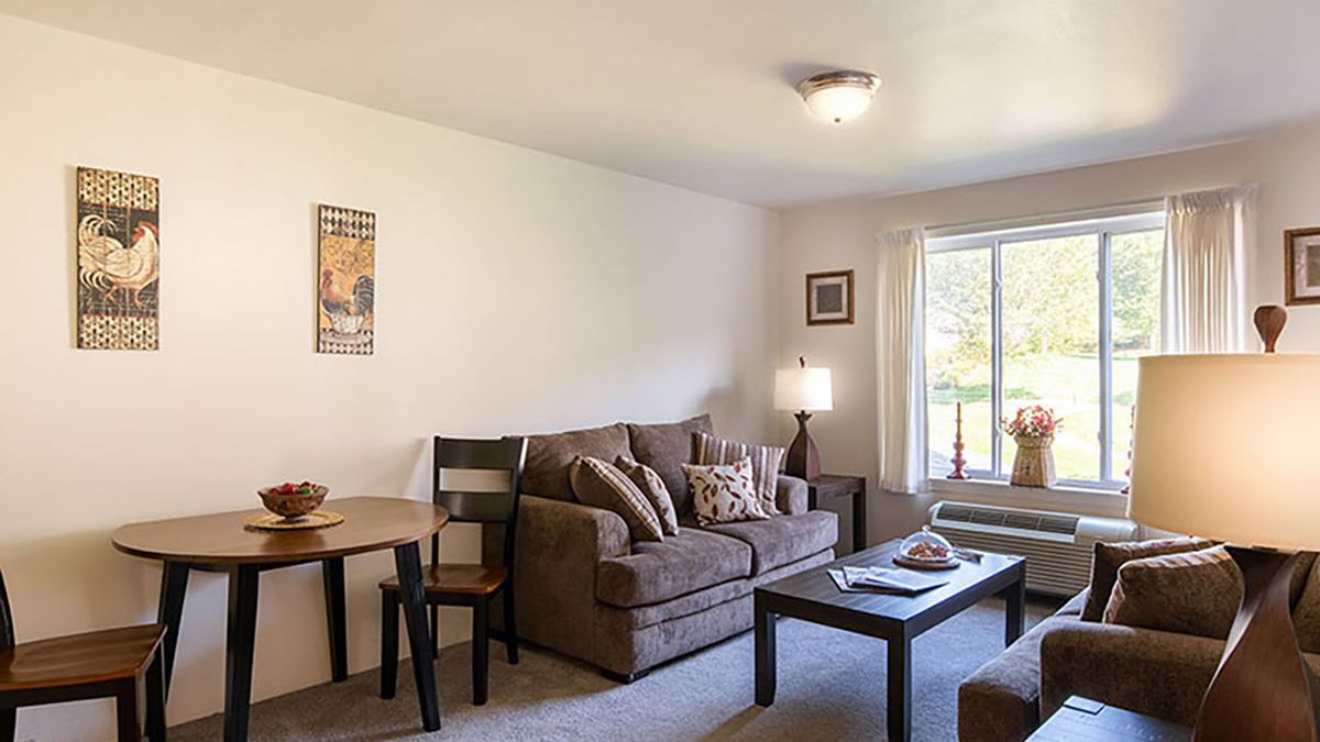 A cozy living room with a sofa, coffee table, and lamp near a window.