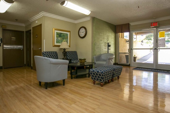 A cozy lobby area with comfortable chairs, a coffee table, and decor elements like a painting and a clock on the wall.