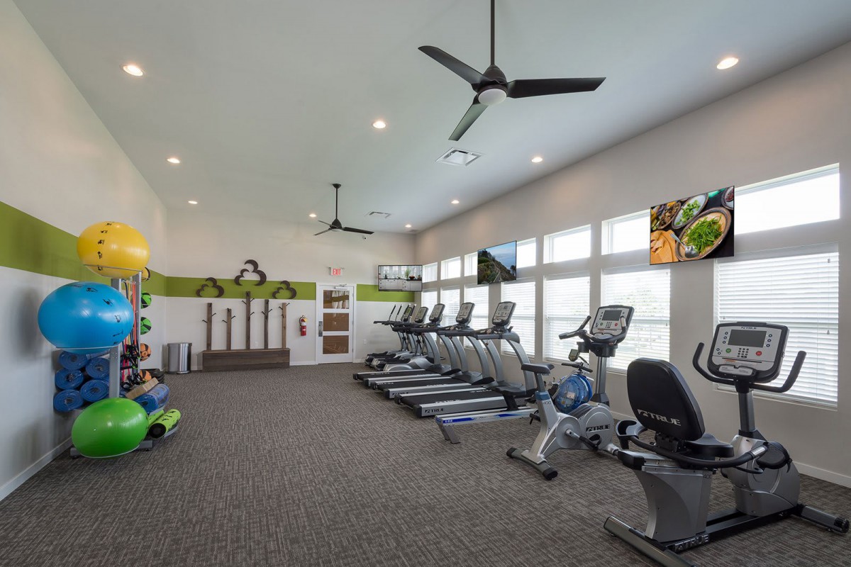 A modern gym with treadmills and various exercise equipment in a spacious, well-lit room.