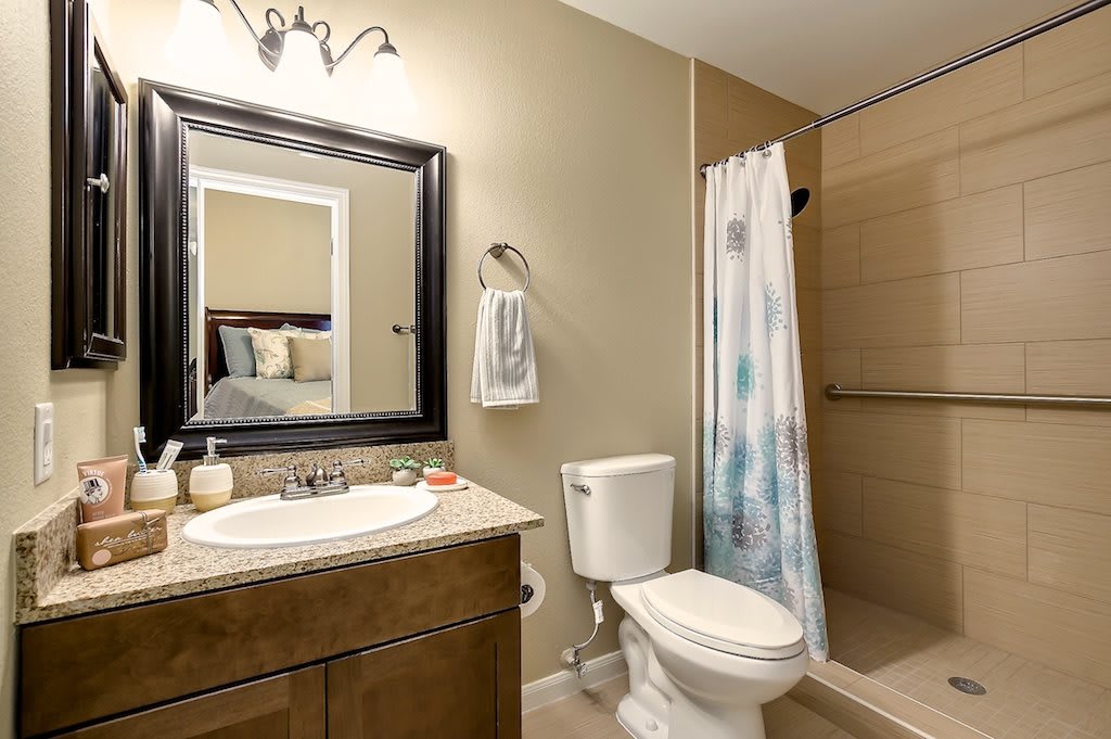 Modern bathroom featuring a sink, toilet, and shower with curtain.