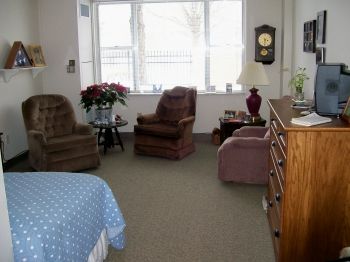 A cozy living room with armchairs and a clock on the wall.