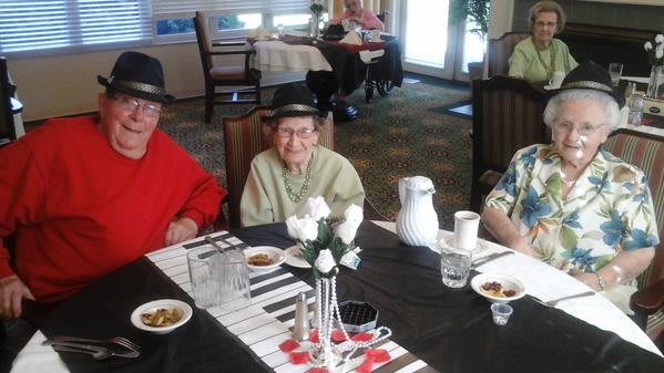 A group of elderly individuals enjoying a meal together, wearing hats and smiling at the table.