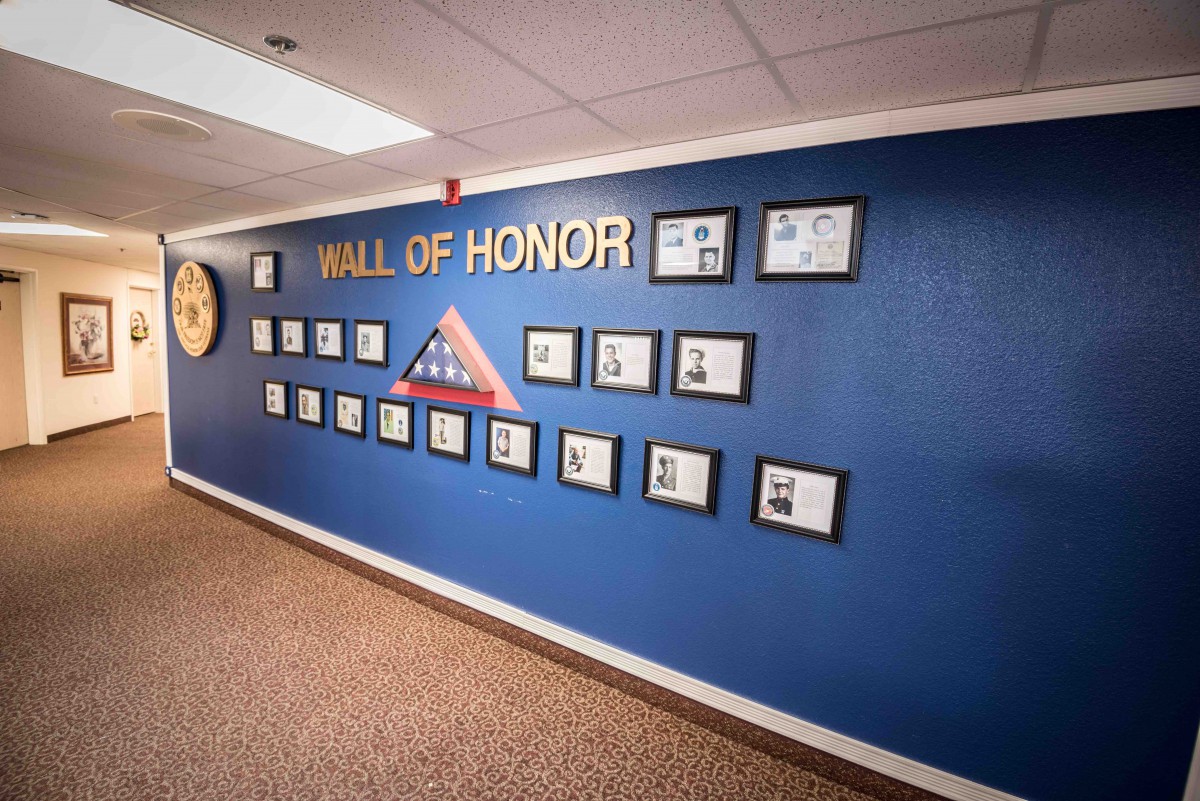 A Wall of Honor featuring framed photos and a tribute display on a blue wall.