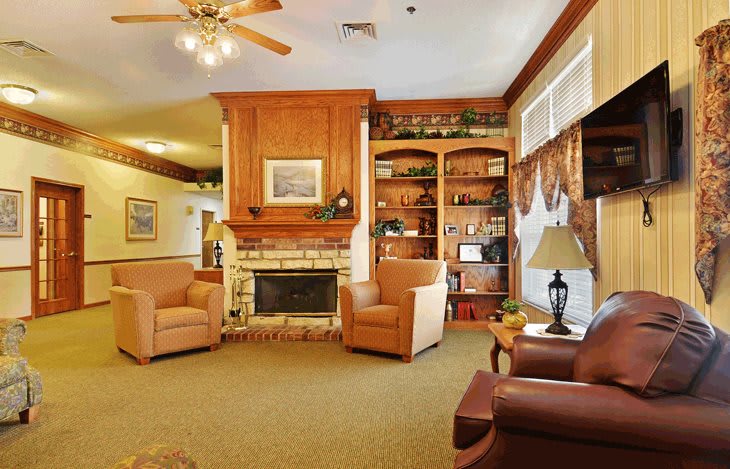 A cozy living room featuring a fireplace, armchairs, and built-in bookshelves.