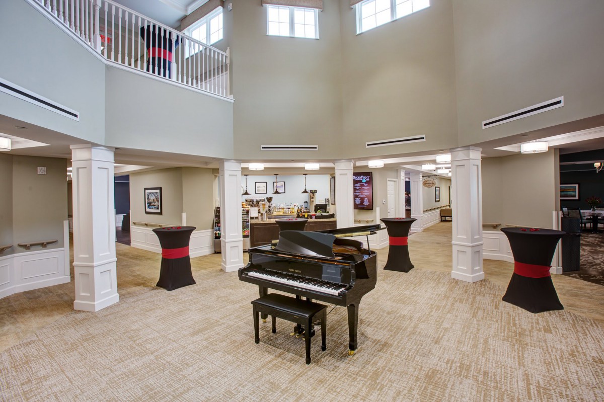 A spacious lobby area featuring a grand piano in the center with elegant architectural design elements.