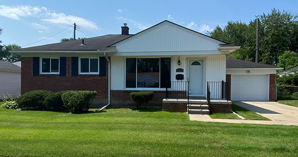 A single-story suburban house with a brick facade and a well-maintained lawn.