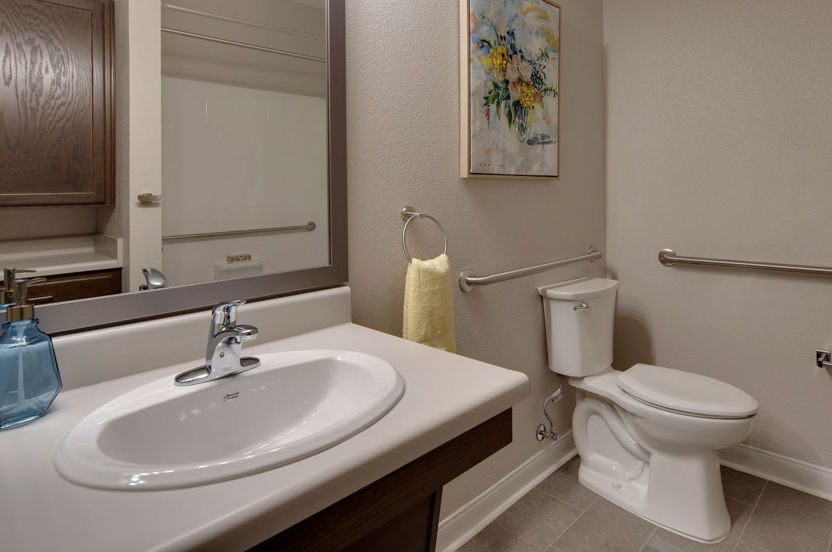 A modern bathroom with a sink, mirror, toilet, and decorative artwork.