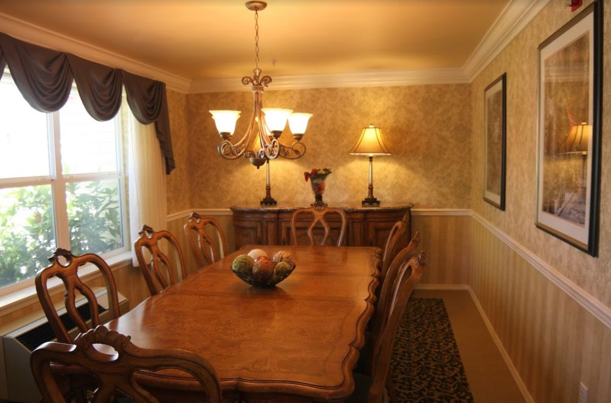 A well-decorated dining room featuring a wooden table with matching chairs, a chandelier, and elegant curtains.