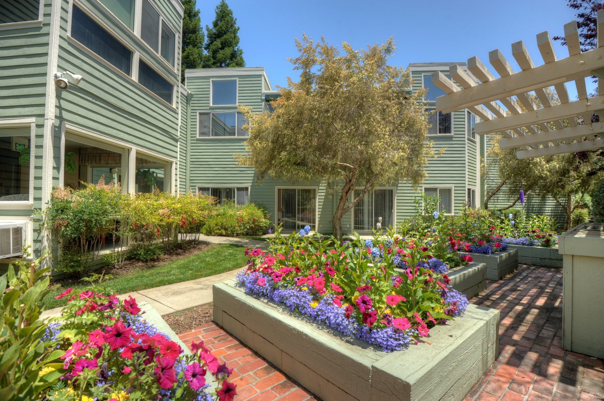 A beautifully landscaped garden with vibrant flowers in front of an apartment building.