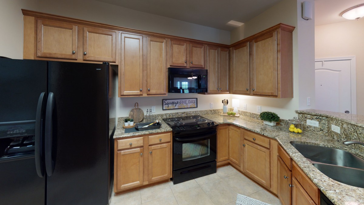 A modern kitchen with wooden cabinets and black appliances.