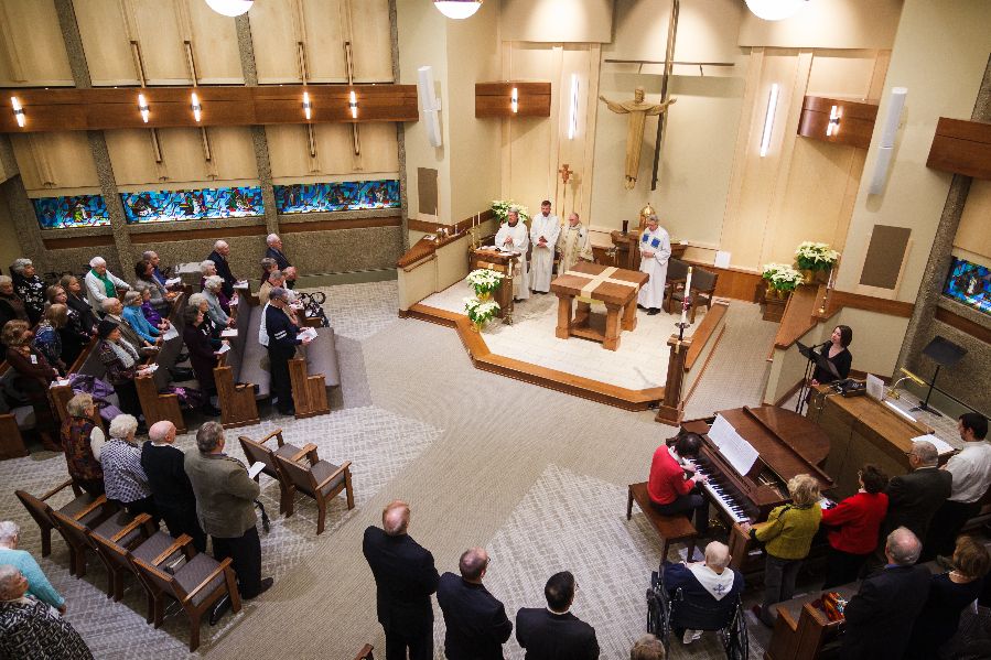 A church service in progress with a congregation gathered and priests at the altar.