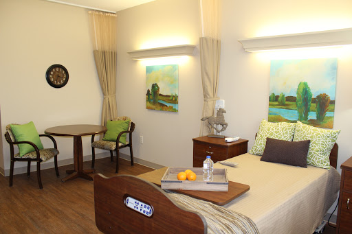 A cozy hospital room with a bed, a small table, and decorative paintings.