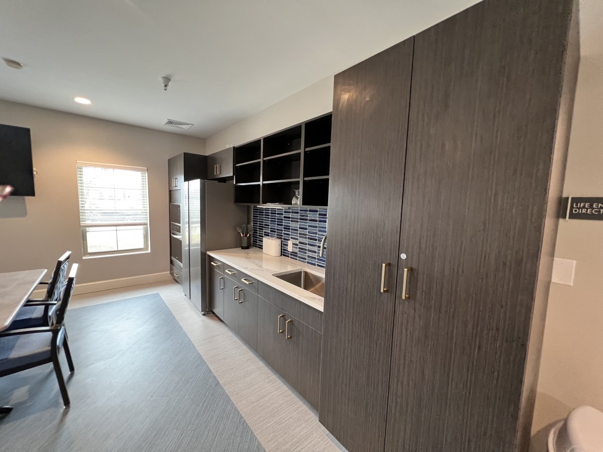 A modern kitchen with dark cabinets and open shelving, featuring a sleek design and ample storage.