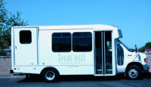 A white shuttle bus parked outdoors on a clear day.