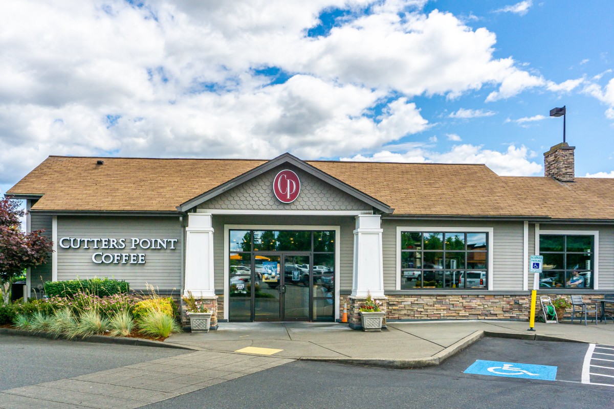 The exterior of a restaurant with a parking lot and a partly cloudy sky.