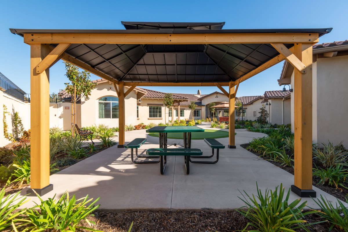 A gazebo with a picnic table in a sunny residential courtyard.