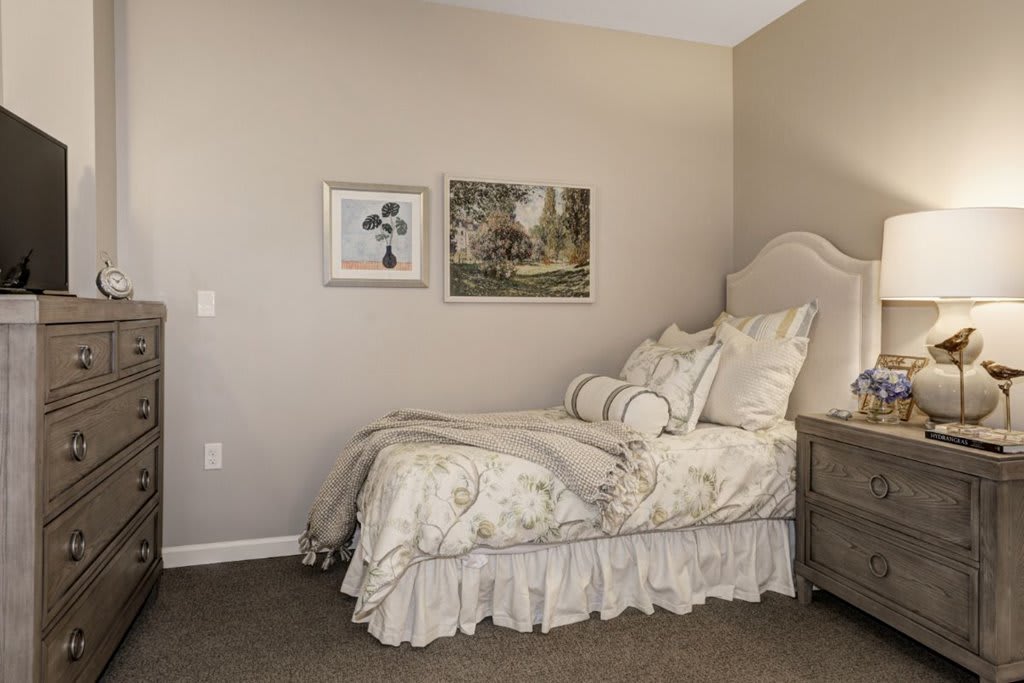 A cozy bedroom with elegant bedding and wall art.