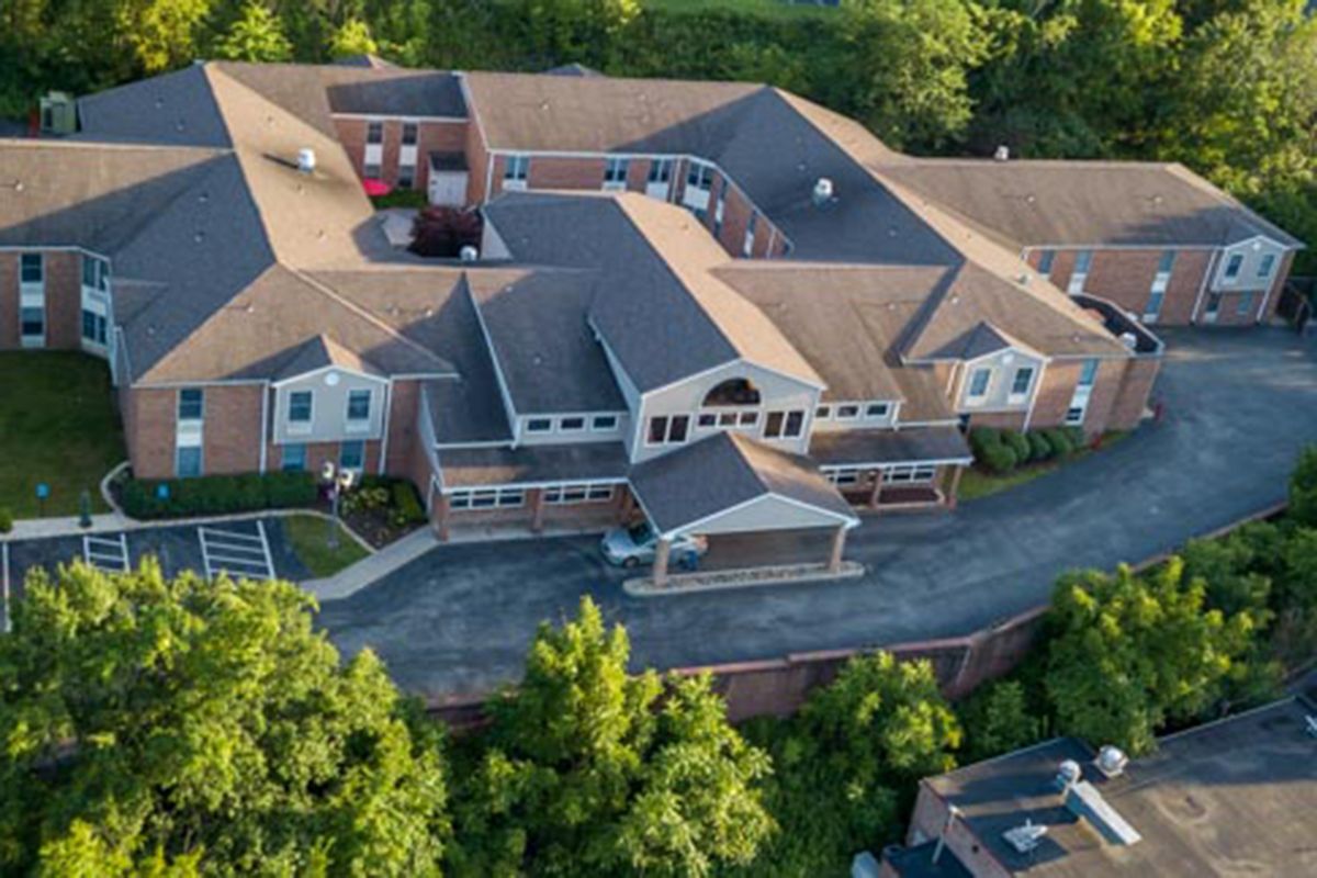 Aerial view of a large building surrounded by lush greenery and a winding driveway.