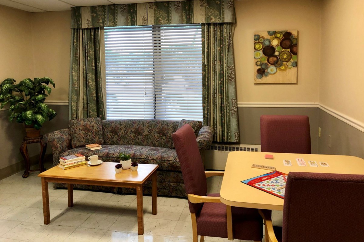 A cozy living room with a sofa, coffee table, and board game setup near a window with curtains.