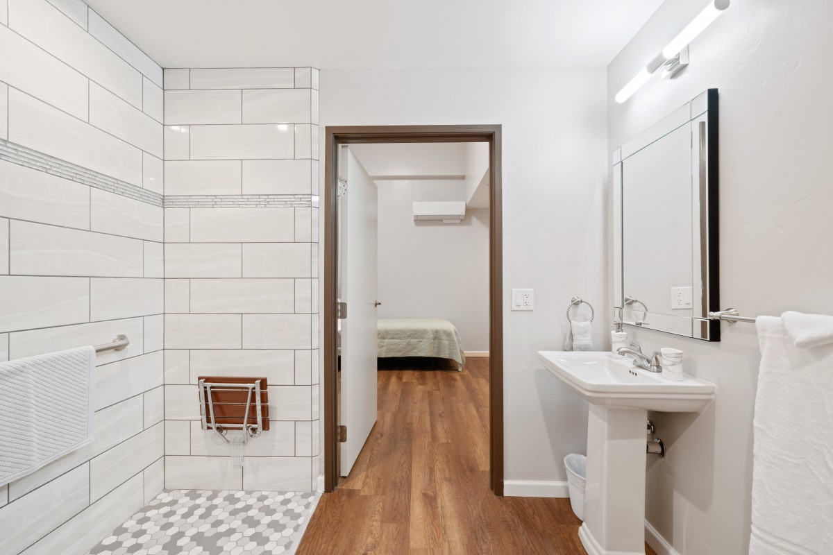 A modern bathroom with minimalist design, featuring a tiled shower and wooden flooring.