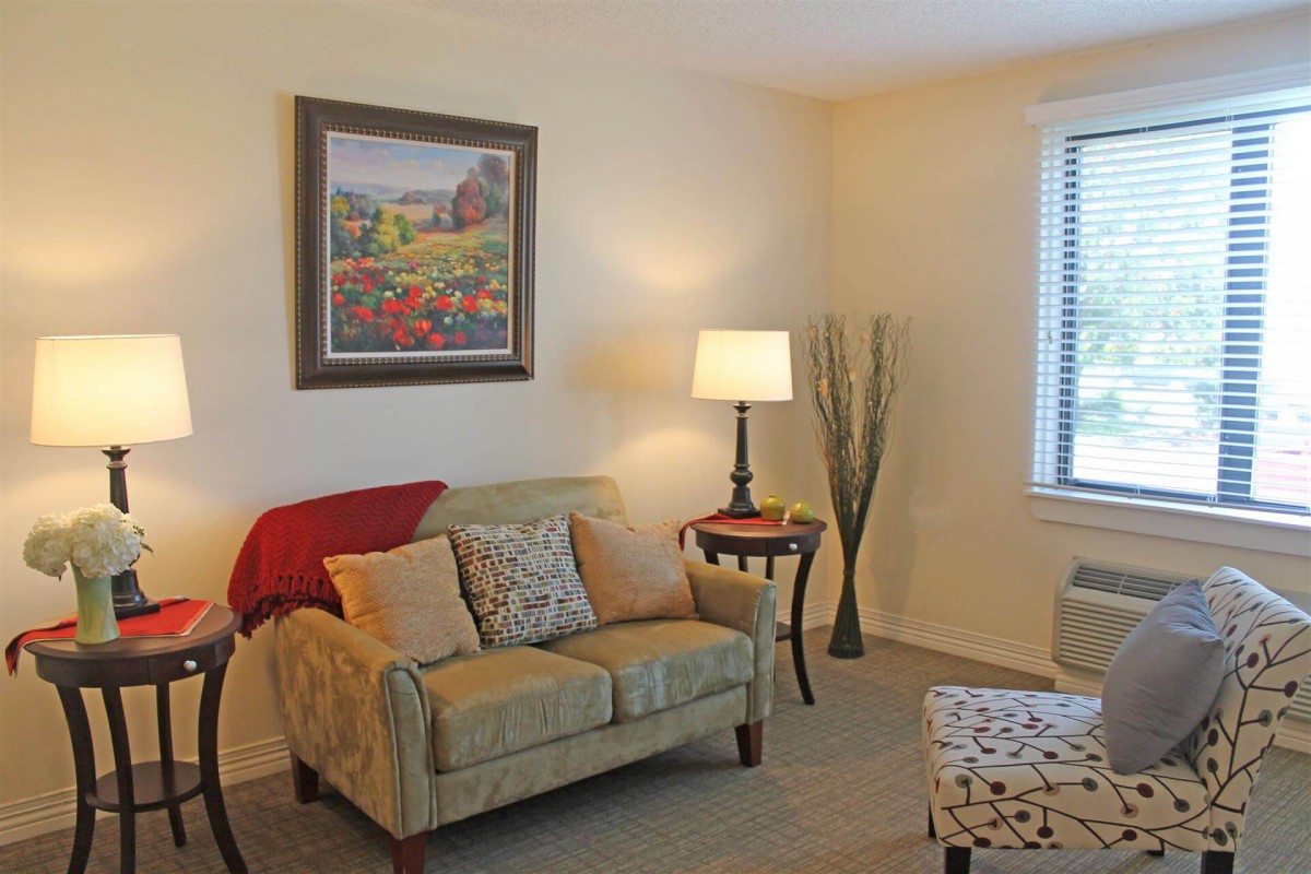 A cozy living room with a sofa, lamp, and a painting above the seating area.