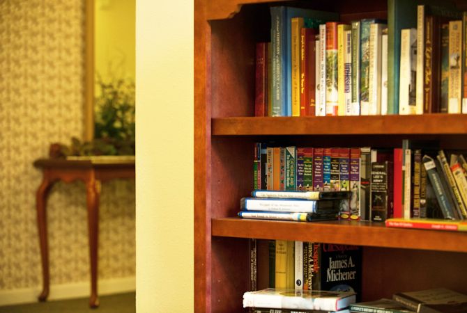 A wooden bookshelf filled with an assortment of books in a cozy library setting.