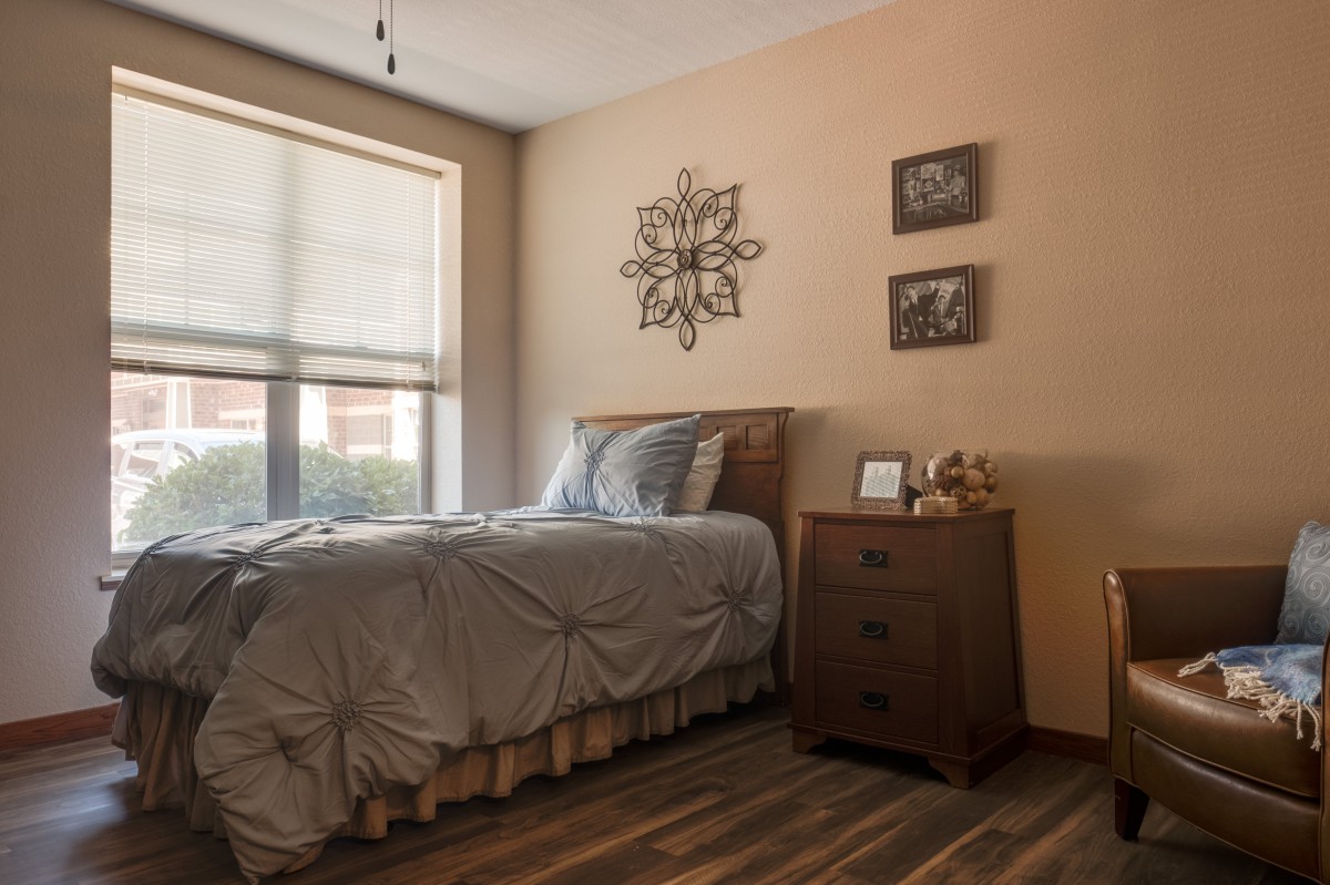 A cozy bedroom with a neatly made bed, nightstand, and decorative wall art.