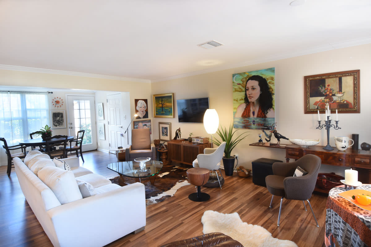 A modern living room featuring a mix of furniture, artwork, and wooden flooring.