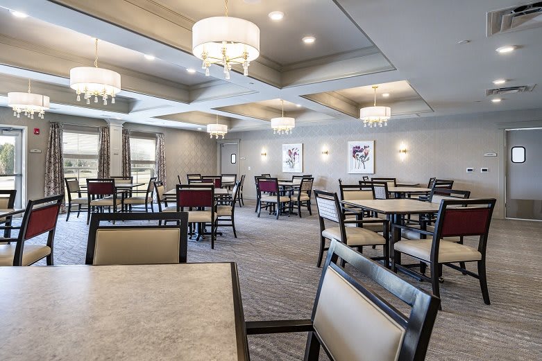 A modern dining room with elegant chandeliers and neatly arranged tables and chairs.