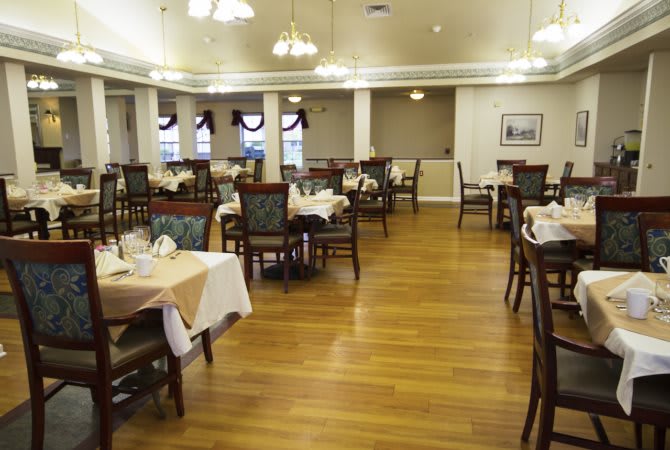 An elegant restaurant dining area with neatly arranged tables and chairs on a wooden floor.