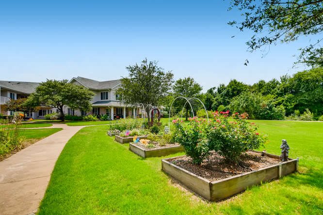 A beautiful house surrounded by a lush garden and well-maintained lawn.