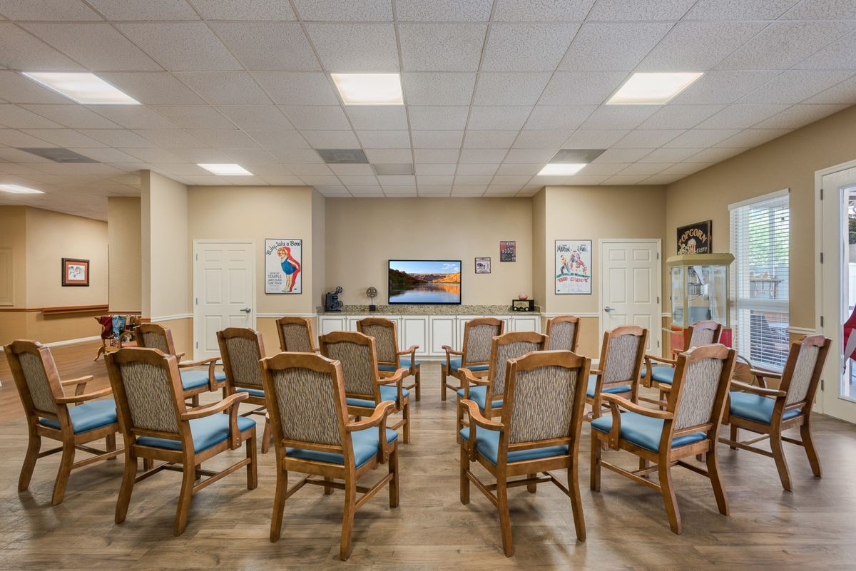 An empty waiting room with rows of chairs facing a television.