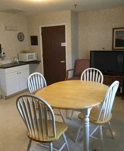 A cozy dining and kitchen area featuring a round table, four chairs, a microwave, and a television.