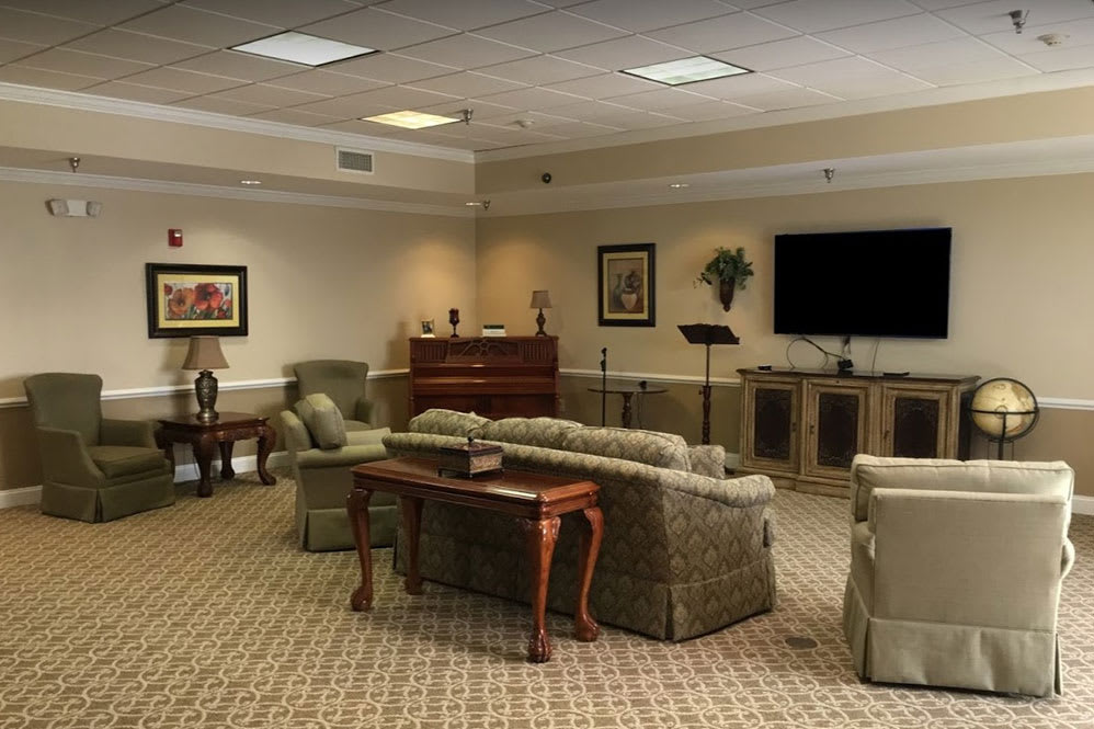 A cozy living room setup with sofas, chairs, and a large television, all arranged on a carpeted floor.