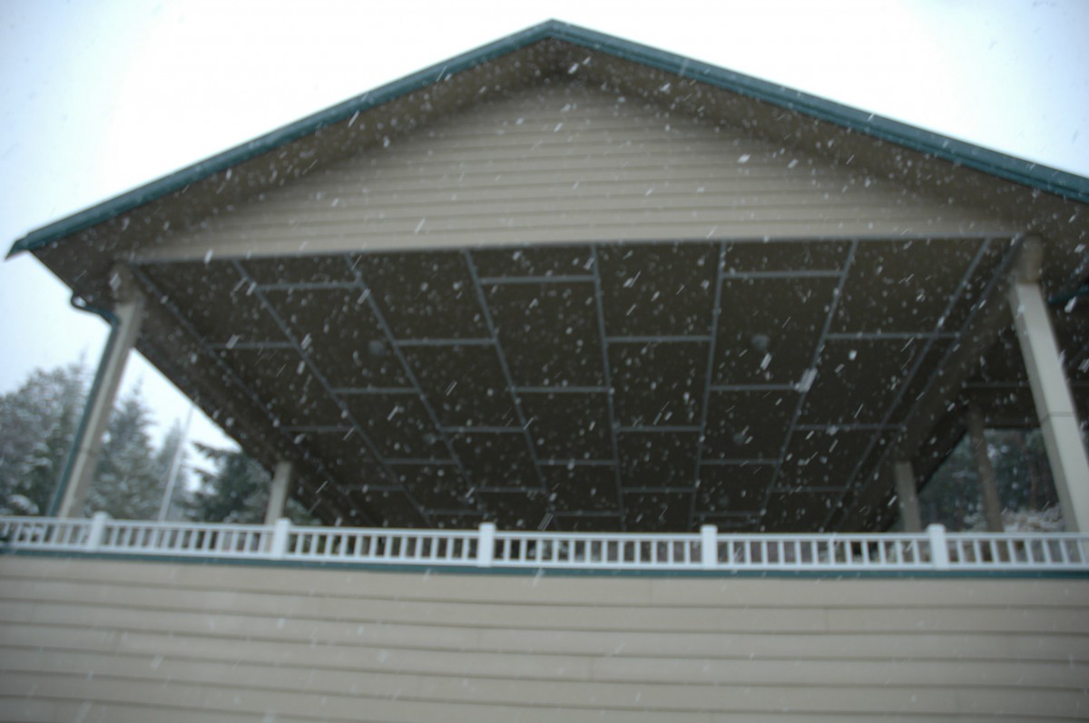 A house with a large roof and snow falling.