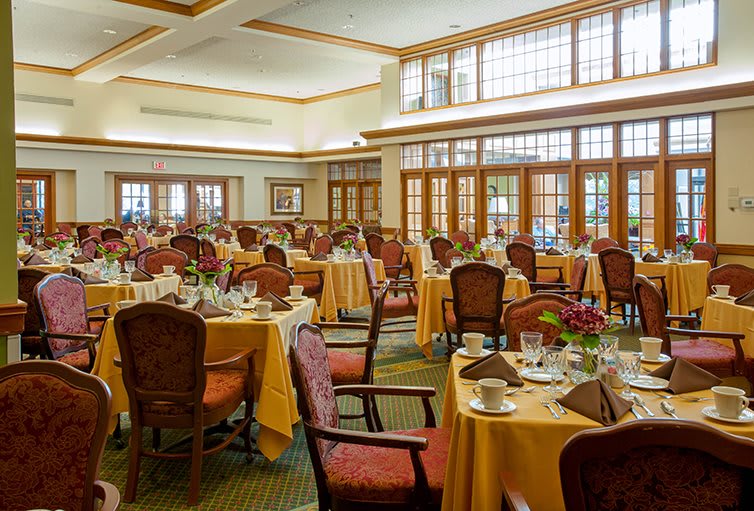 An elegant dining room set up with tables and chairs, ready for guests.
