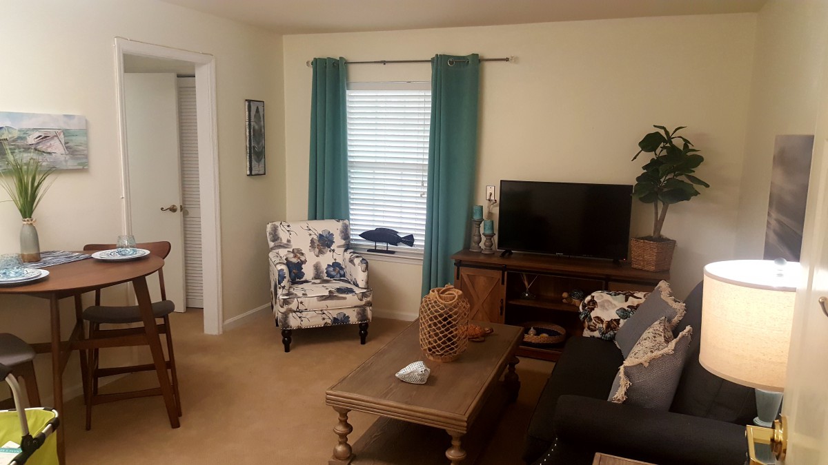 A cozy living room with a sofa, armchair, coffee table, and TV.