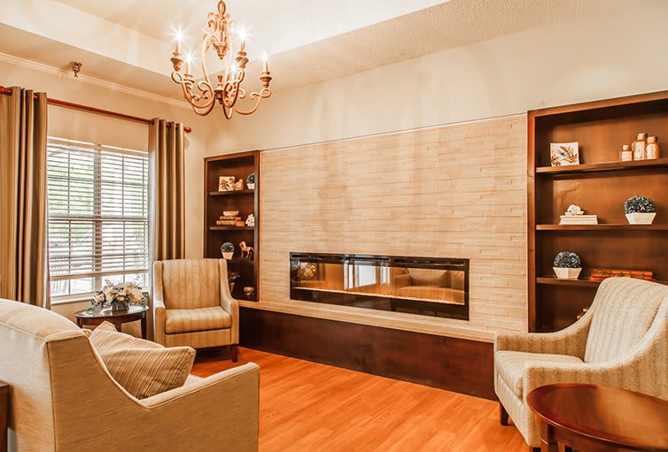 A warm and inviting living room featuring a modern fireplace, elegant chandelier, and comfortable seating.