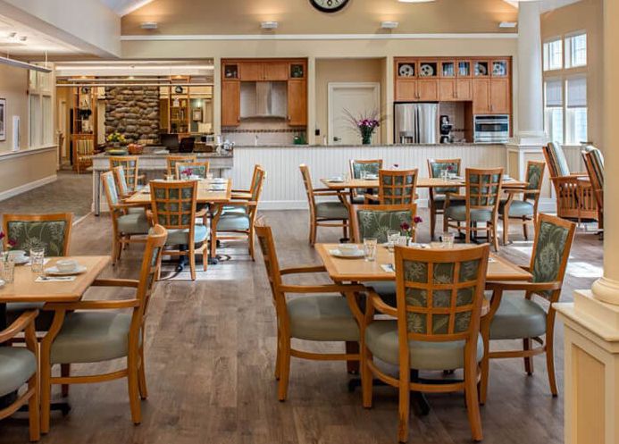 An empty dining area with wooden tables and chairs, featuring a modern and cozy interior design.
