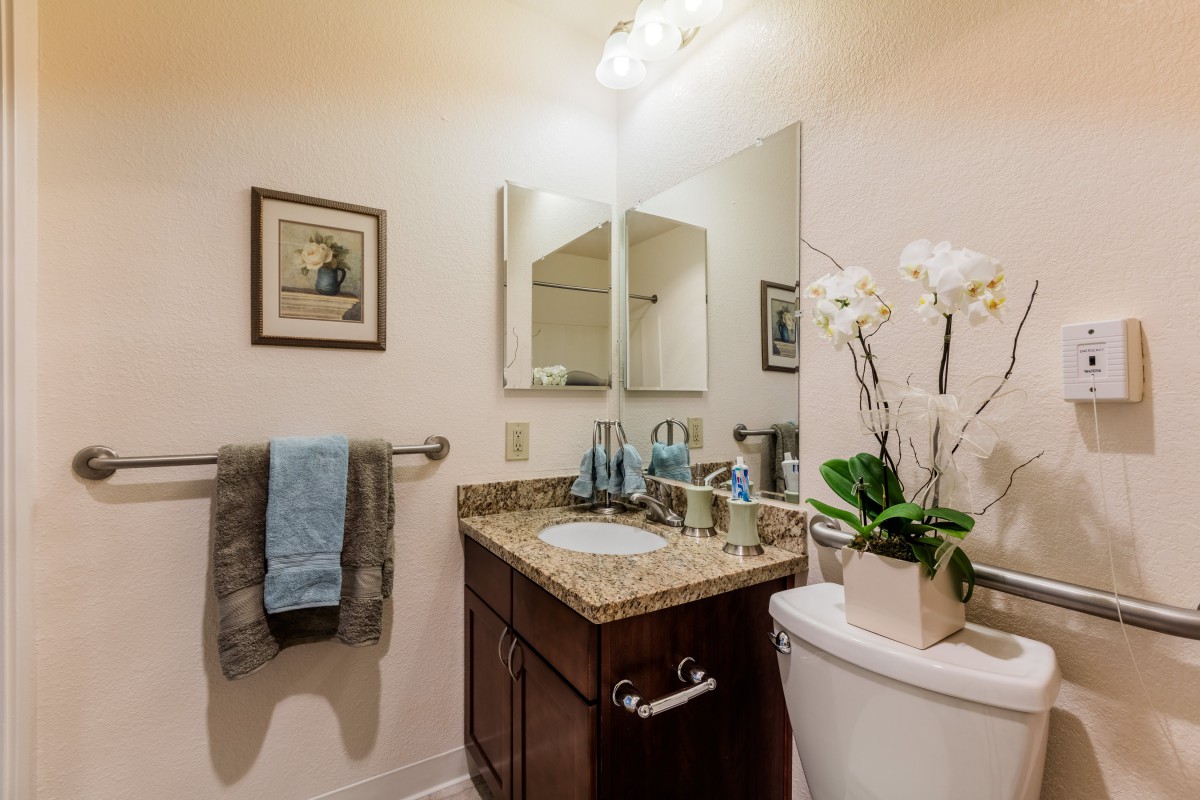 A well-decorated bathroom with a granite countertop, mirror, and stylish decor.